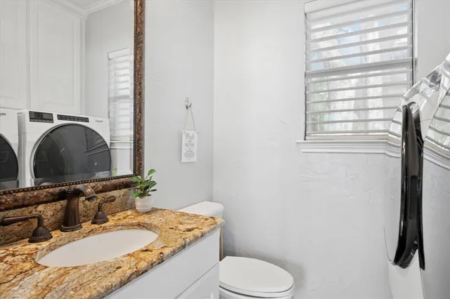 a bathroom with a granite countertop sink toilet and mirror