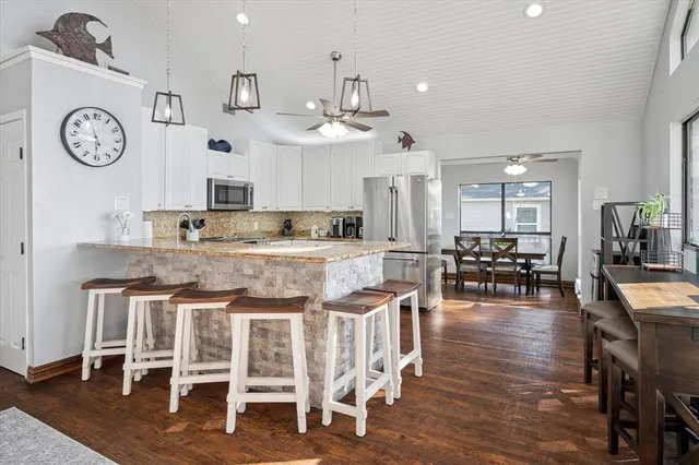 a kitchen with stainless steel appliances granite countertop a dining table chairs stove and cabinets