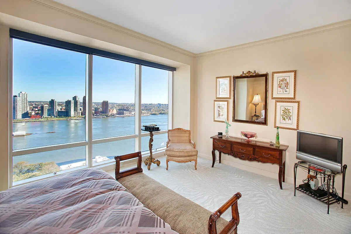 845 United Nations Plaza, Unit 32B Manhattan, NY 10017 - Photo 7 of 9 a bedroom with a bed a large window and walk in closet