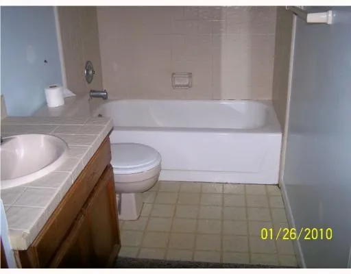 a bathroom with a granite countertop sink and a toilet