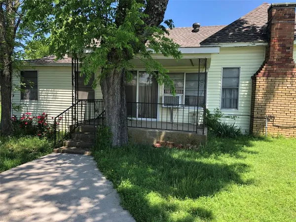 a view of a house with a small yard and a large tree front of it