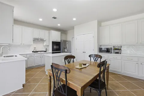 a kitchen with a dining table chairs and white cabinets