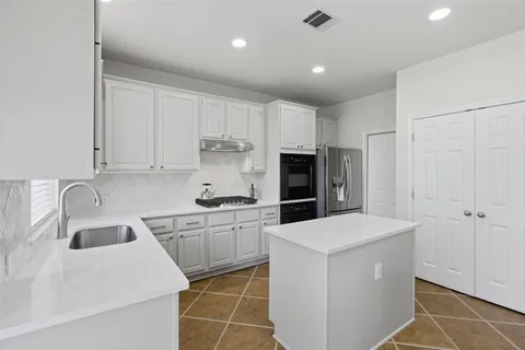 a kitchen that has a sink a stove and white stainless steel appliances