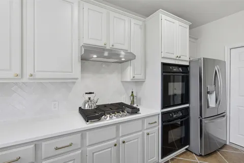 a kitchen with stainless steel appliances granite countertop a refrigerator a stove and white cabinets