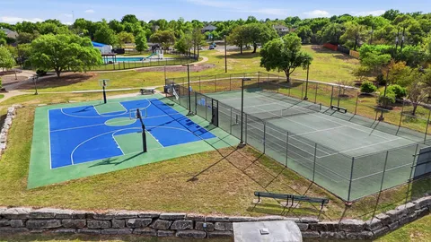 a view of a tennis ground with large trees