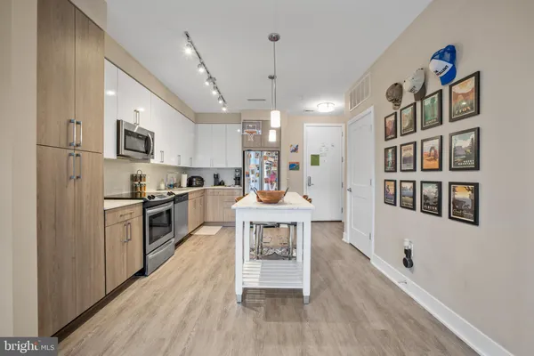 a kitchen with stainless steel appliances granite countertop a refrigerator a stove top oven a sink dishwasher and white cabinets with wooden floor