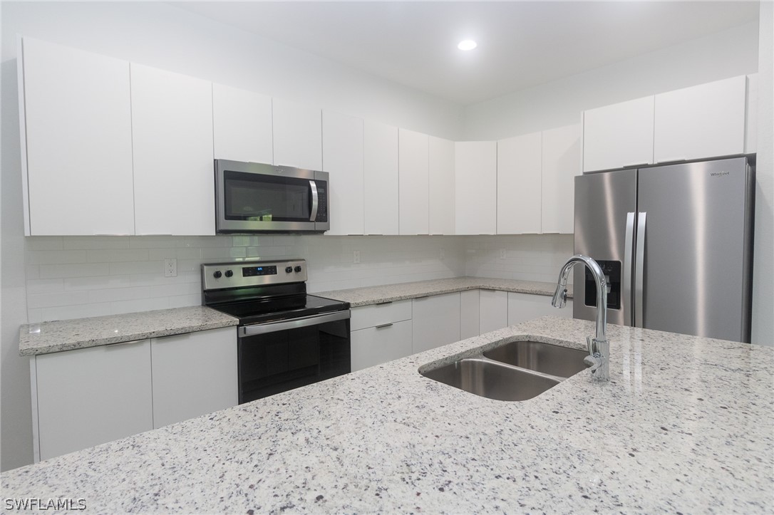 a kitchen with stainless steel appliances granite countertop a sink a stove a microwave and refrigerator