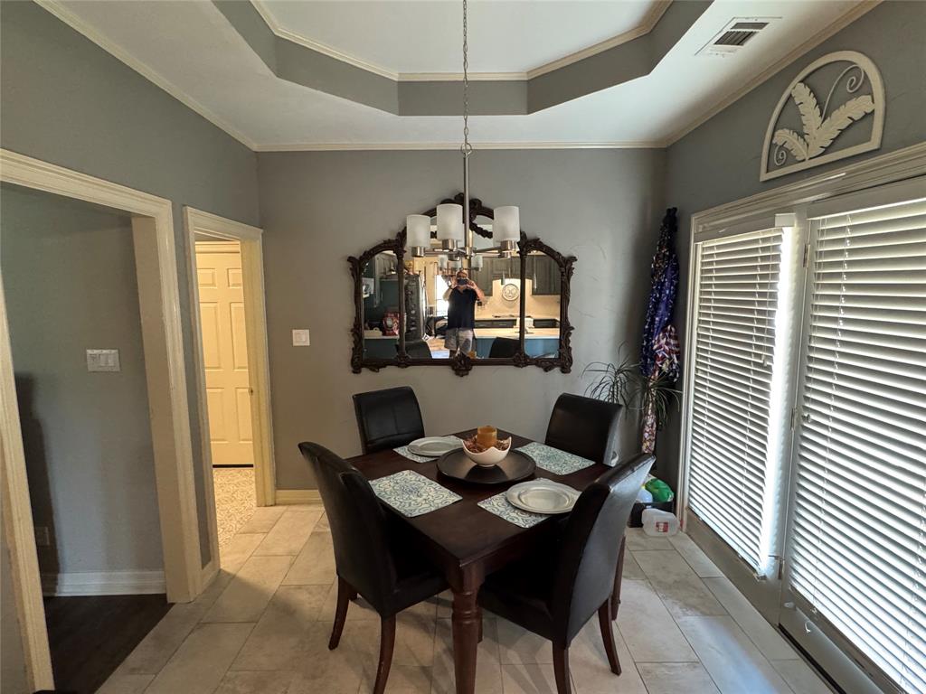 1762 Timber Ridge Circle Corinth, TX 76210 - Photo 10 of 26 Recessed tray ceiling with crown molding, tiled flooring, built-in window blinds, and a contemporary chandelier