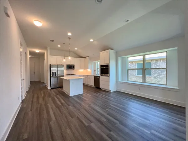 a large kitchen with stainless steel appliances kitchen island granite countertop a stove a sink and a microwave
