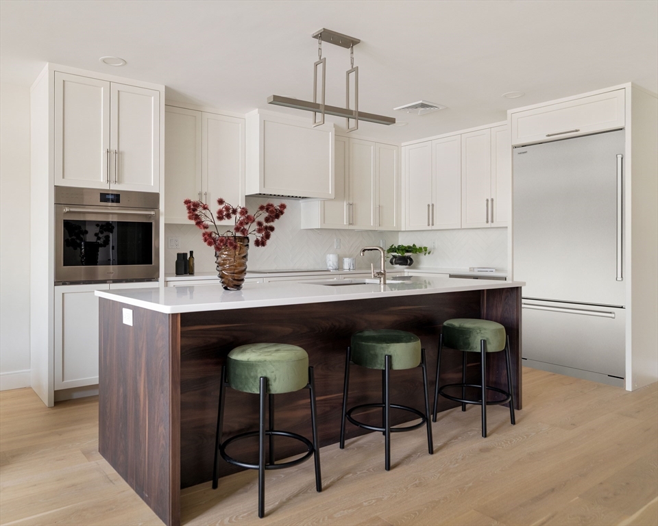 20 Kinmonth Road, Unit 203 Newton, MA 02468 - Photo 3 of 18 a kitchen with granite countertop a table chairs stove and cabinets