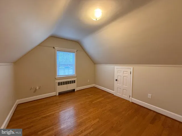 a view of an empty room with wooden floor and windows