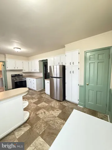 a large kitchen with stainless steel appliances kitchen island granite countertop a refrigerator and a stove top oven