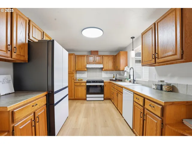 a kitchen with stainless steel appliances granite countertop a refrigerator a sink dishwasher a stove with wooden cabinets