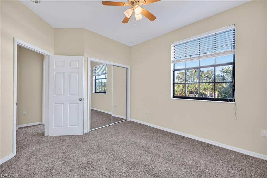7666 Bristol Circle Naples, FL 34120 - Photo 11 of 20 an empty room with chandelier fan and windows