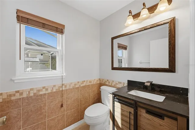 a bathroom with a toilet a sink a mirror and a window