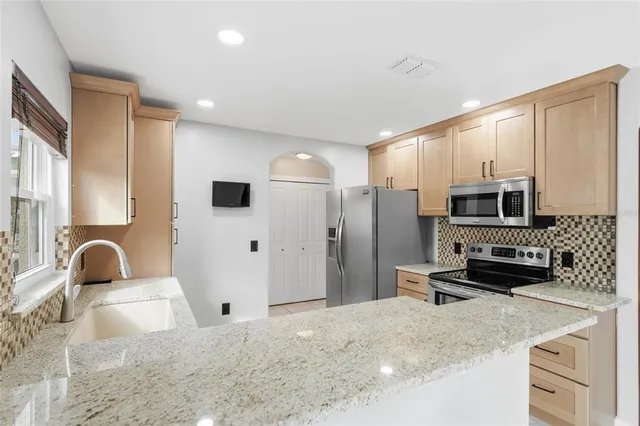 a kitchen with stainless steel appliances a sink a stove a microwave a refrigerator a counter top space and cabinets