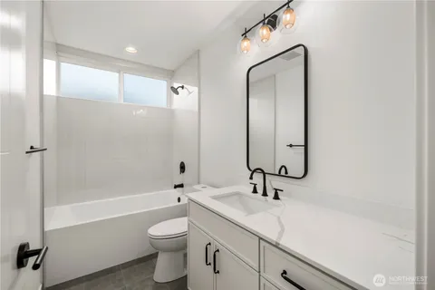 a bathroom with a granite countertop sink a toilet and shower