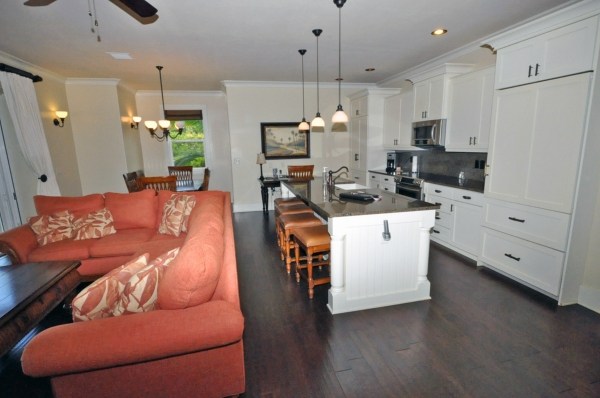 a large white kitchen with a white countertops a stove a sink and a chandelier