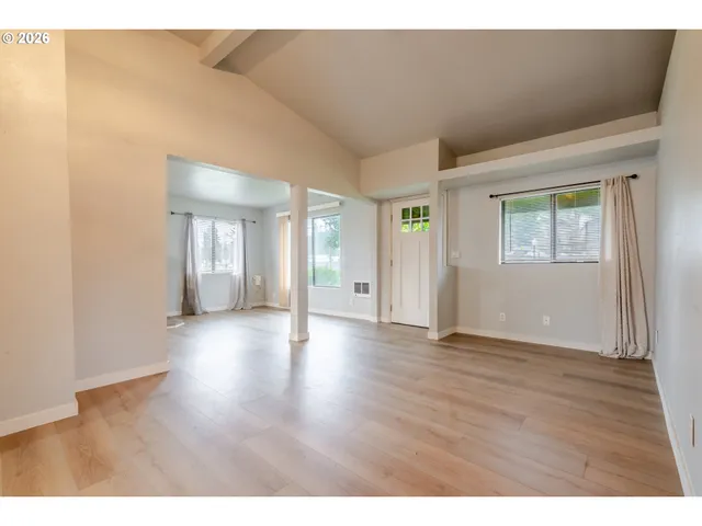 a view of an empty room with wooden floor and windows