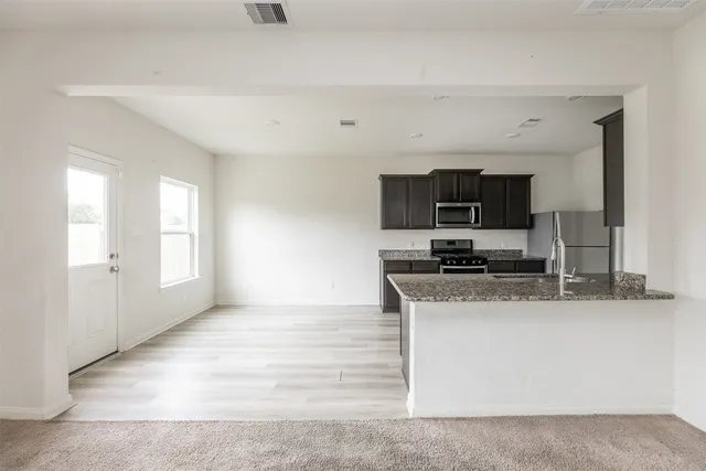 a kitchen with stainless steel appliances granite countertop a sink a stove top oven a refrigerator and dishwasher