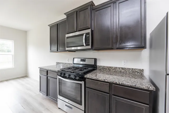 a kitchen with granite countertop wooden cabinets stainless steel appliances and a window