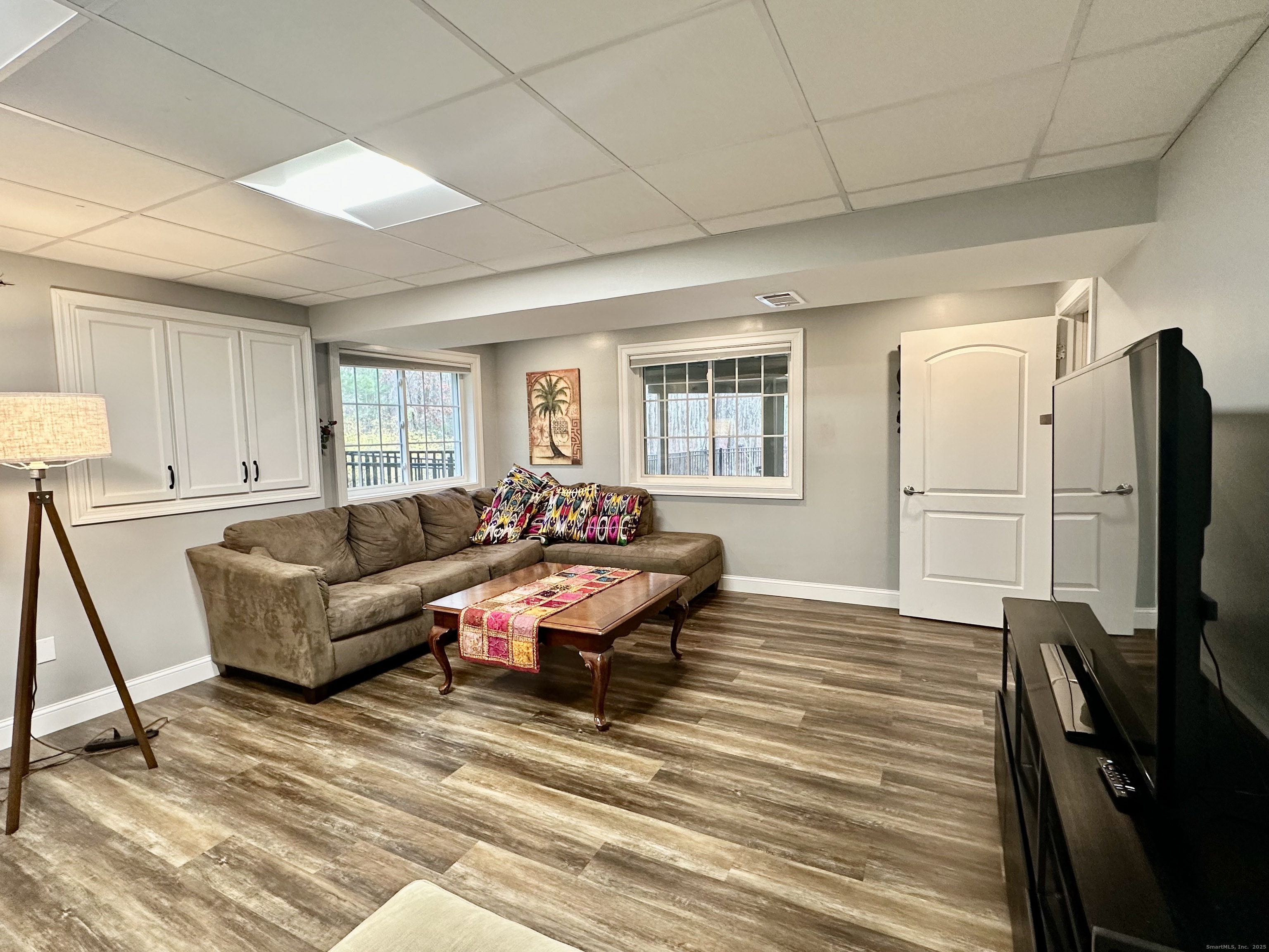a living room with furniture a flat screen tv and a refrigerator