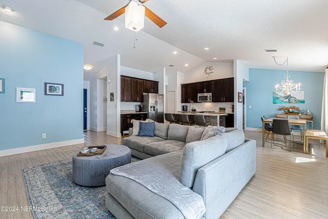 a kitchen with kitchen island granite countertop wooden cabinets a refrigerator a stove a sink and a oven with wooden floor