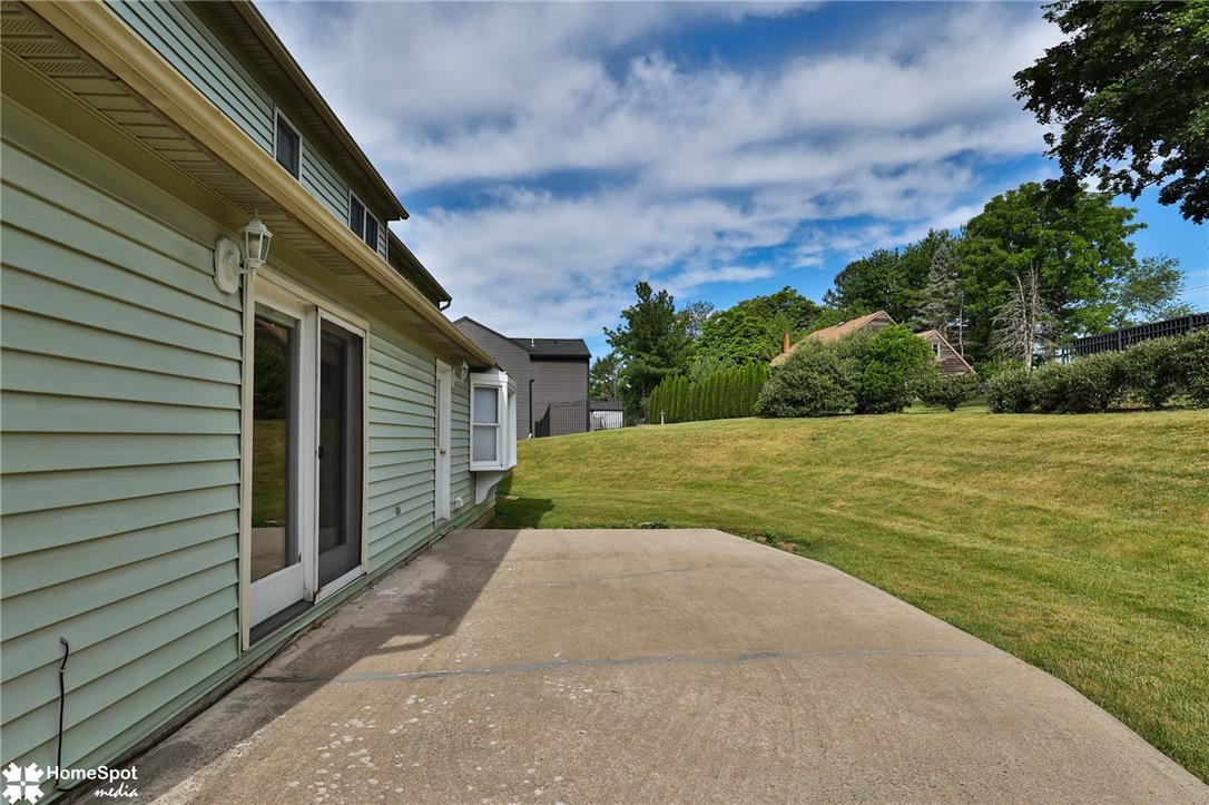 4059 Wedgewood Road Allentown, PA 18104 - Photo 63 of 72 A spacious concrete patio extends from the home, offering ample outdoor living space within a manicured yard.