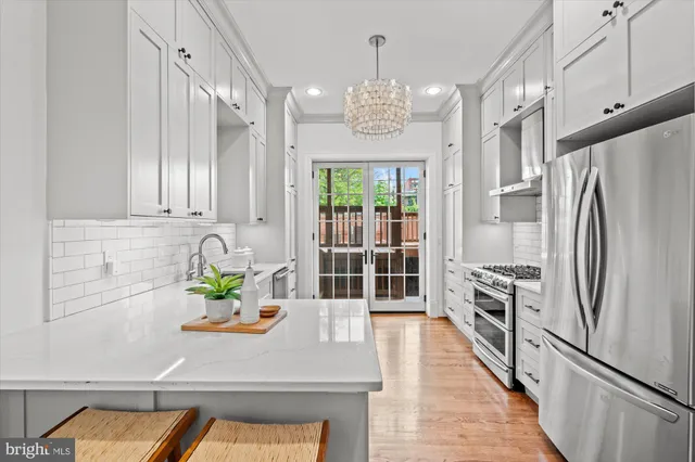 a kitchen with stainless steel appliances a dining table chairs and chandelier