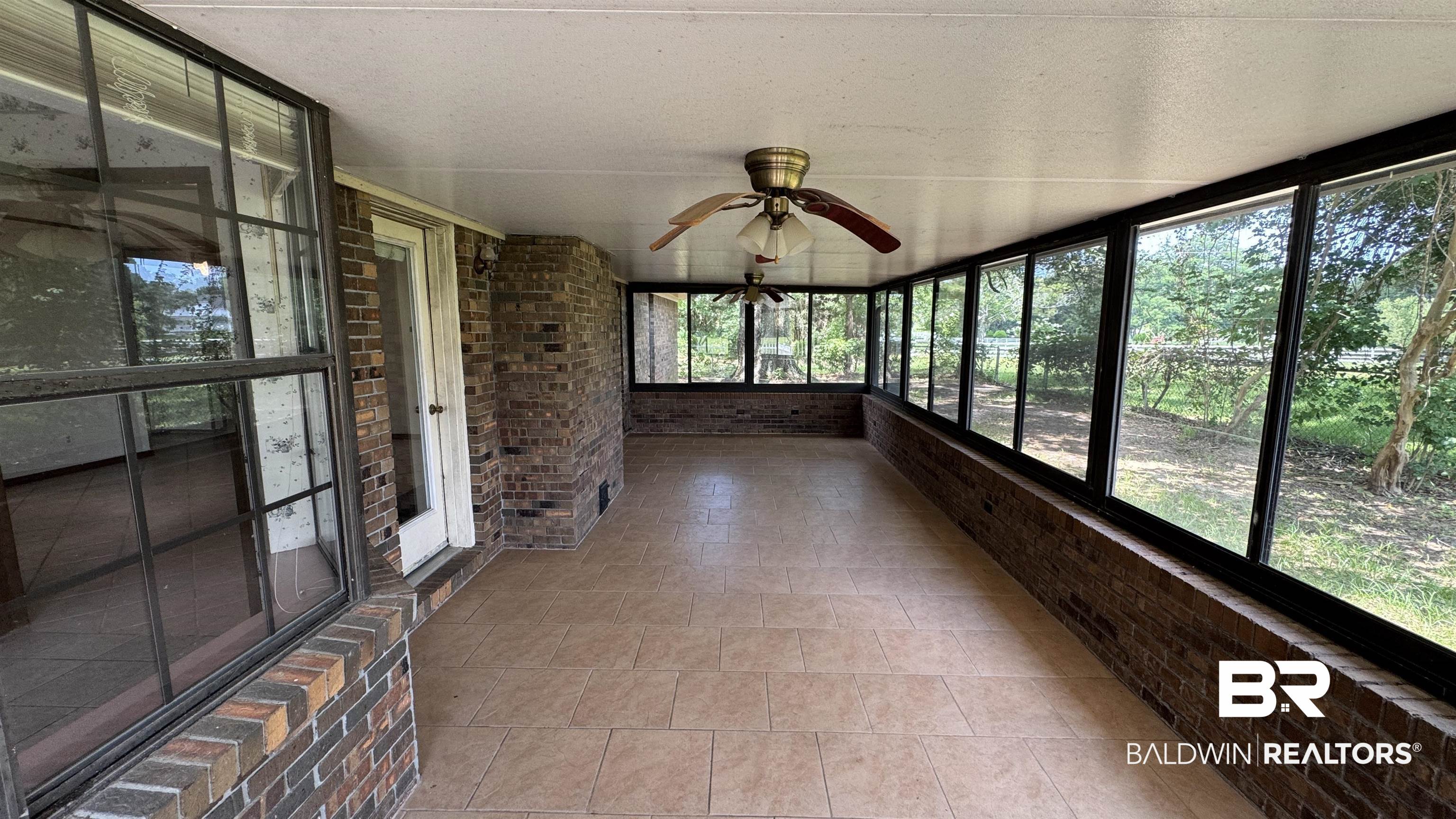 33370 Highway 98 Lillian, AL 36549 - Photo 41 of 58 Enclosed sunroom featuring a brick knee wall, multiple pane windows, and a tiled floor