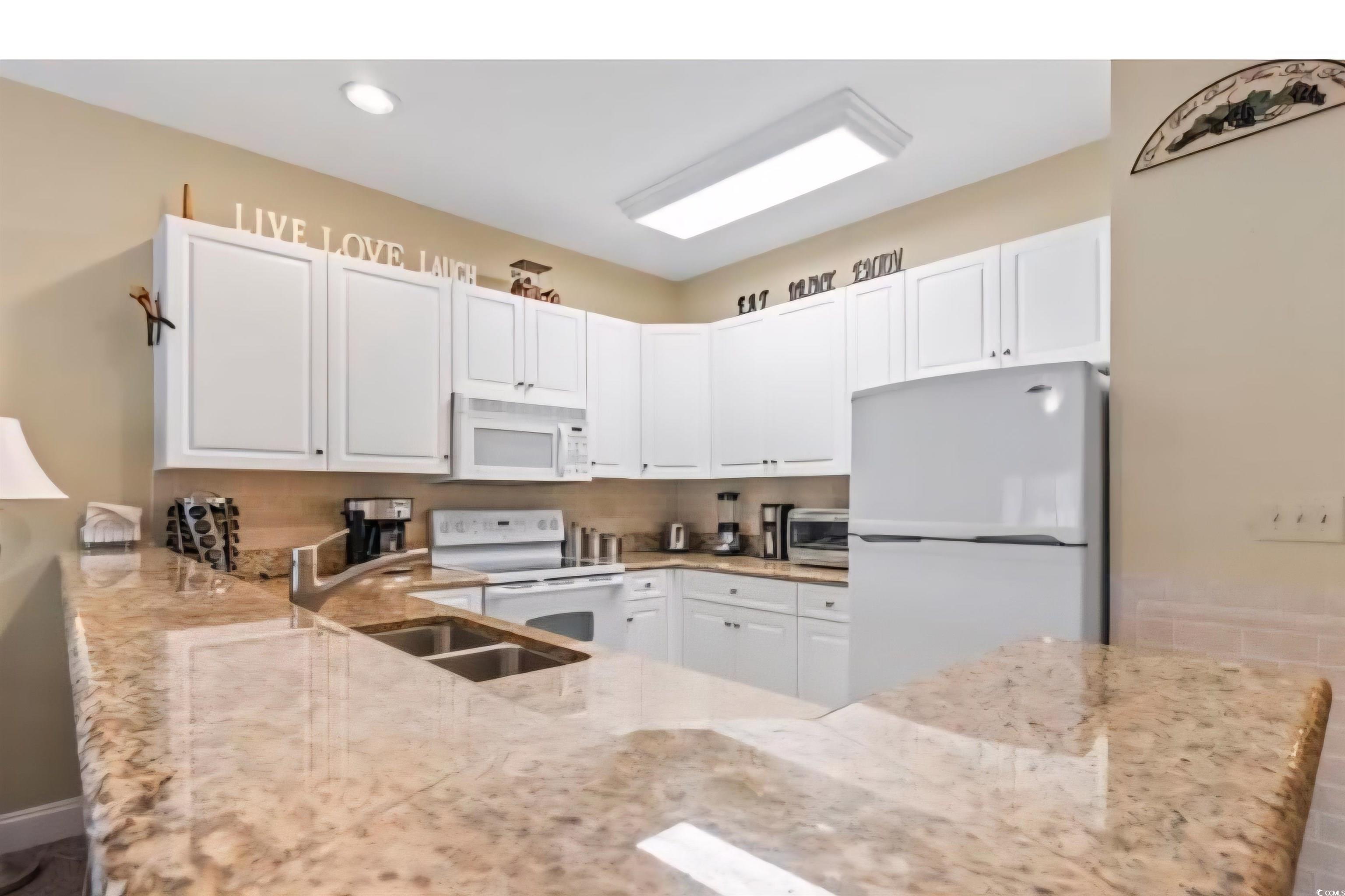 1009 World Tour Boulevard Myrtle Beach, SC 29579 - Photo 25 of 36 Kitchen with white appliances, white cabinetry, and light stone countertops