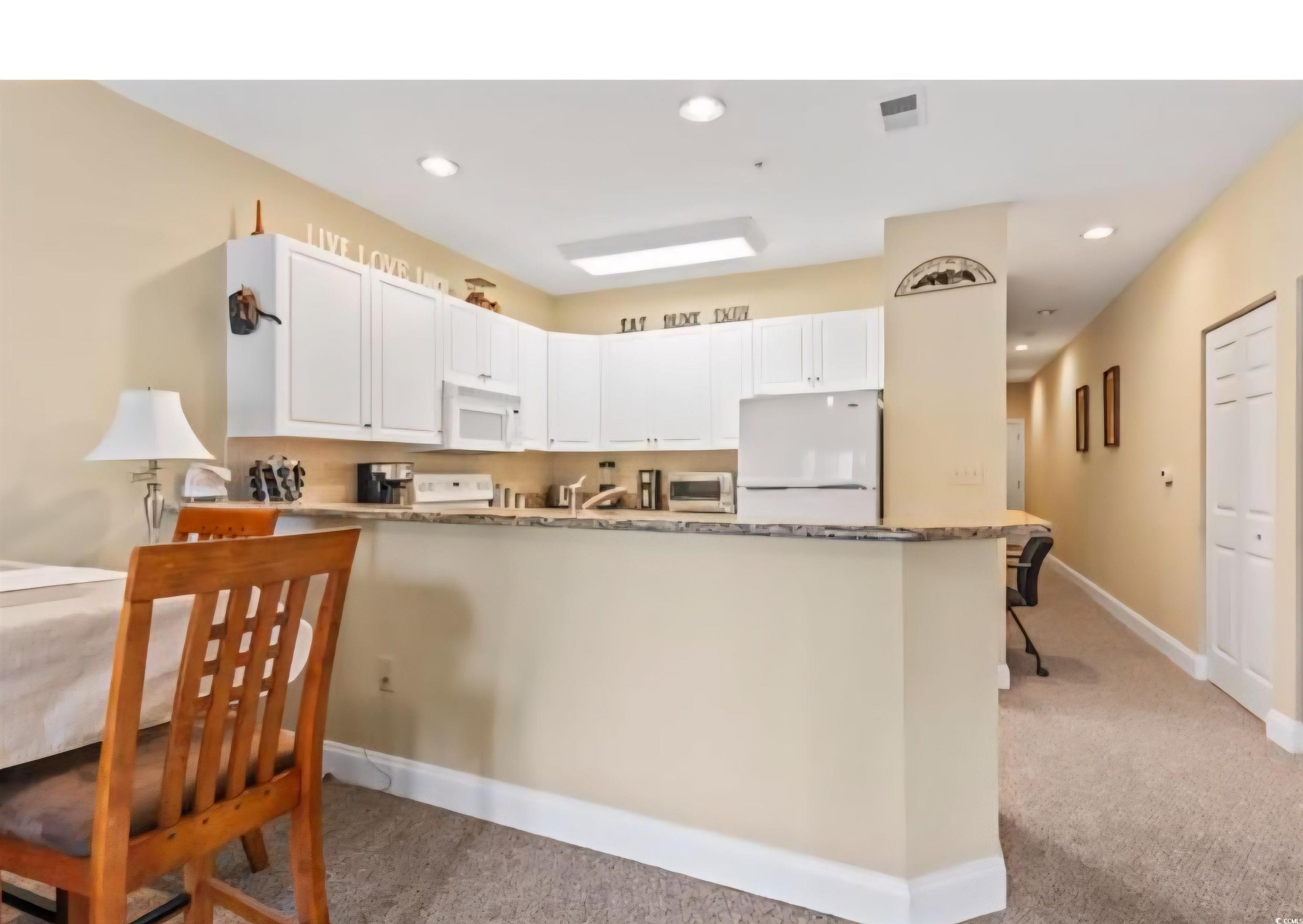 1009 World Tour Boulevard Myrtle Beach, SC 29579 - Photo 30 of 36 Kitchen featuring a peninsula, white appliances, white cabinets, light colored carpet, and recessed lighting