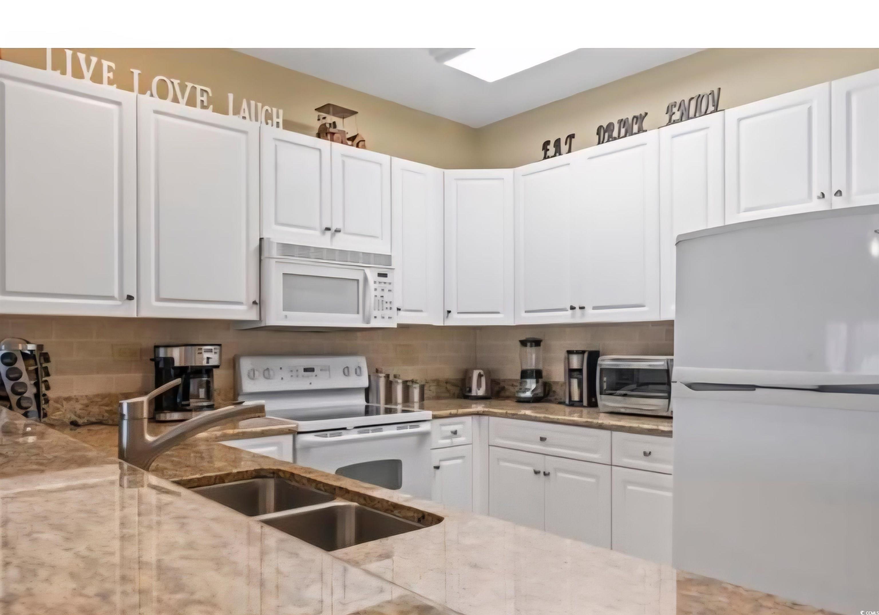 1009 World Tour Boulevard Myrtle Beach, SC 29579 - Photo 31 of 36 Kitchen featuring white appliances, white cabinetry, tasteful backsplash, and light stone countertops