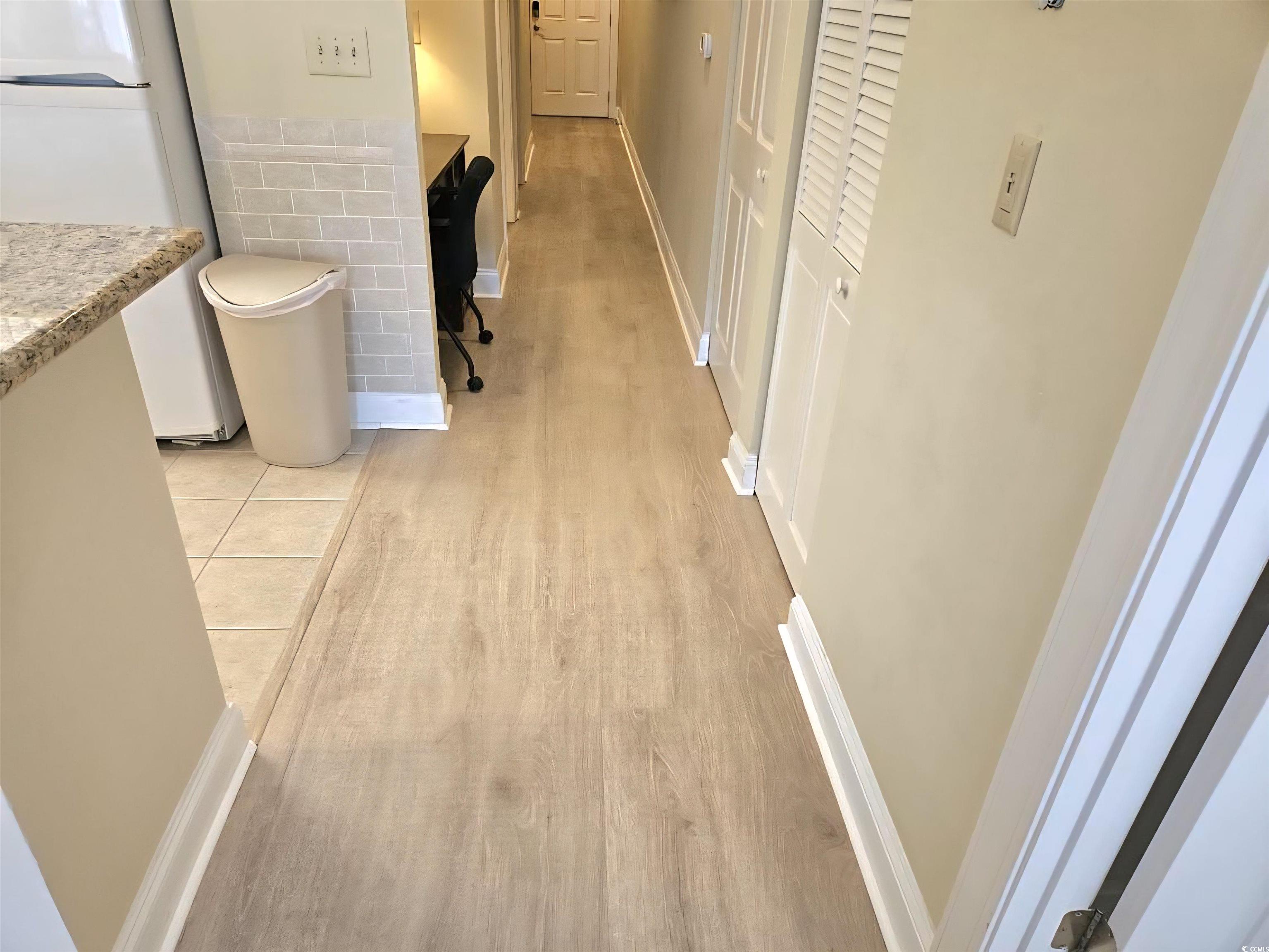 1009 World Tour Boulevard Myrtle Beach, SC 29579 - Photo 5 of 36 new floors , Hallway with light wood-style flooring, a wainscoted wall, and tile walls