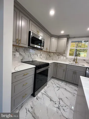 a kitchen with stainless steel appliances kitchen island granite countertop a sink and a stove top oven with wooden floor