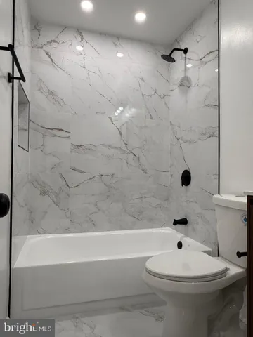 a bathroom with a toilet a sink a mirror a bathtub and vanity