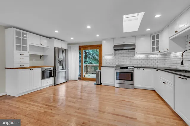 a large kitchen with stainless steel appliances granite countertop a large counter top a stove a sink and a refrigerator