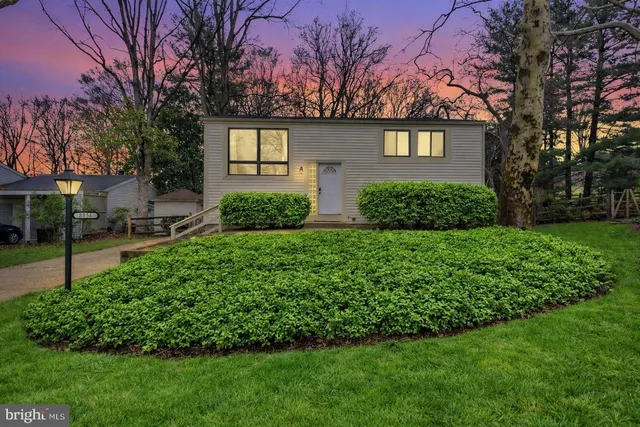 a front view of a house with a yard and green space