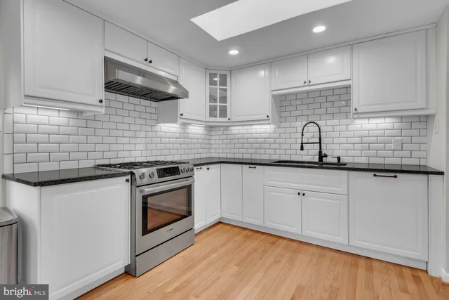 a kitchen with stainless steel appliances granite countertop a sink a stove and cabinets