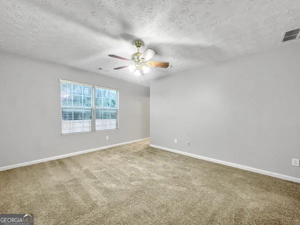 an empty room with windows and chandelier fan