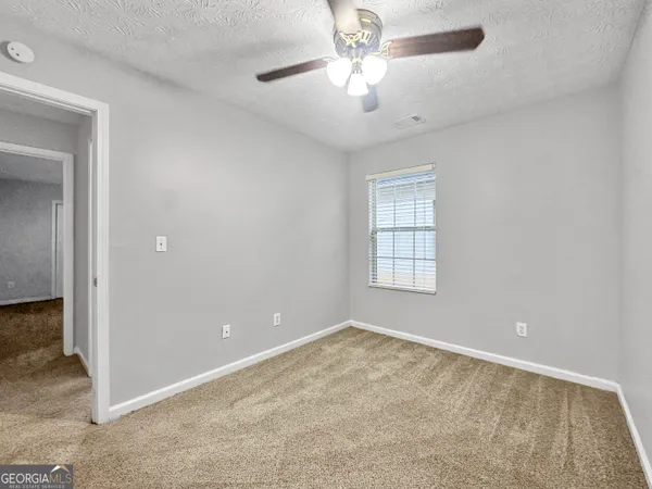 an empty room with chandelier fan and windows