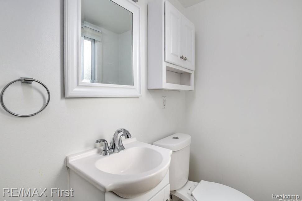 1349 Devonshire Road Grosse Pointe, MI 48230 - Photo 11 of 26 White vanity with an integrated sink, polished chrome faucet, and a framed mirror