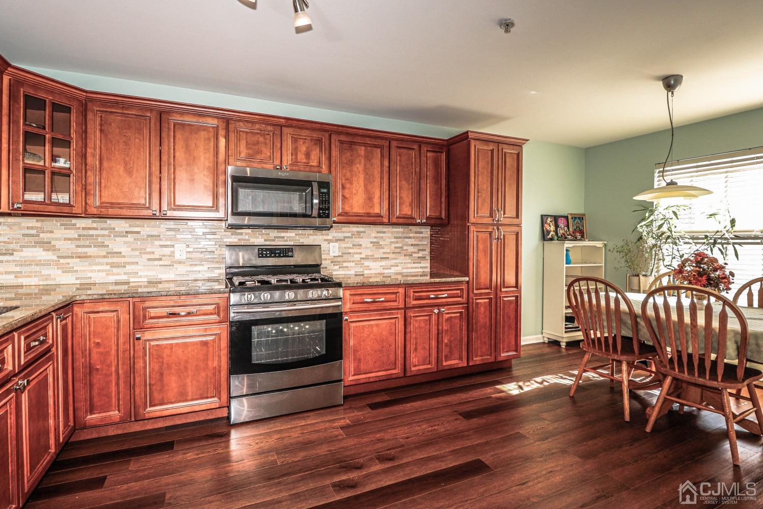 8 Prestwick Way Edison, NJ 08820 - Photo 6 of 27 a kitchen with stainless steel appliances granite countertop wooden cabinets a stove a sink and dishwasher with wooden floor