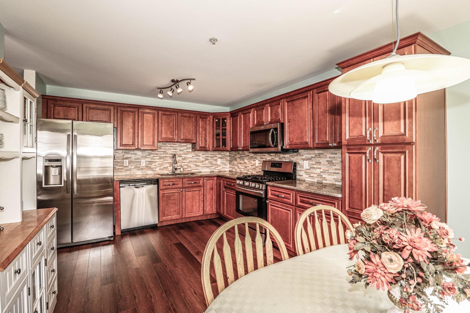 8 Prestwick Way Edison, NJ 08820 - Photo 9 of 27 a kitchen with stainless steel appliances granite countertop a refrigerator a sink dishwasher a stove with wooden cabinets and floor
