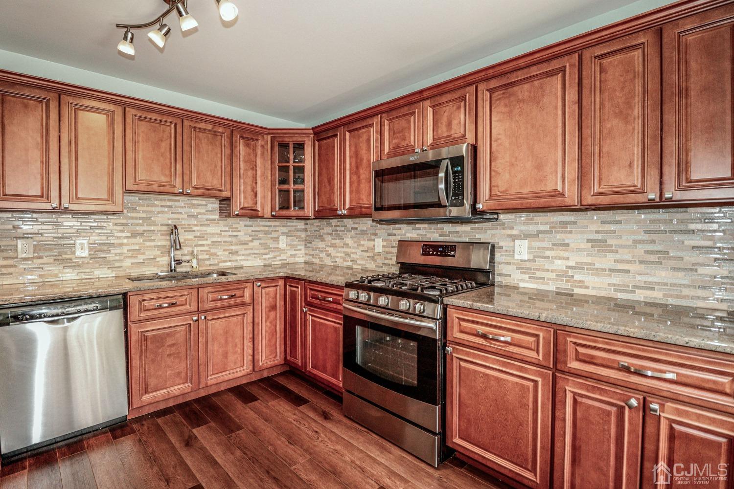 8 Prestwick Way Edison, NJ 08820 - Photo 10 of 27 a kitchen with granite countertop wooden cabinets a stove top oven and granite counter tops