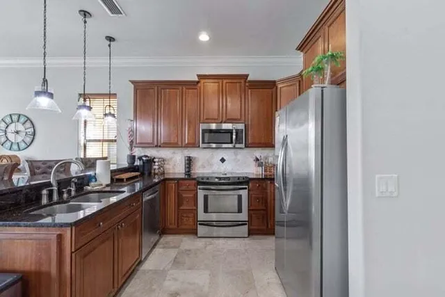 a kitchen with stainless steel appliances granite countertop a stove a sink and a refrigerator