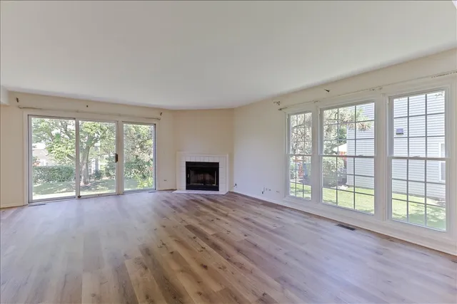 wooden floor fireplace and windows in an empty room