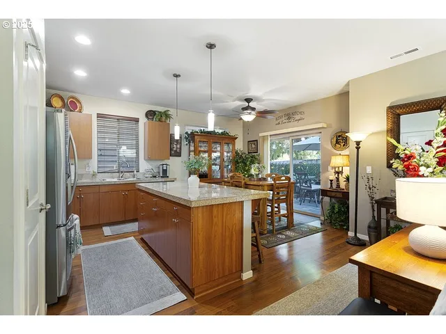 a kitchen with stainless steel appliances kitchen island granite countertop refrigerator and cabinets
