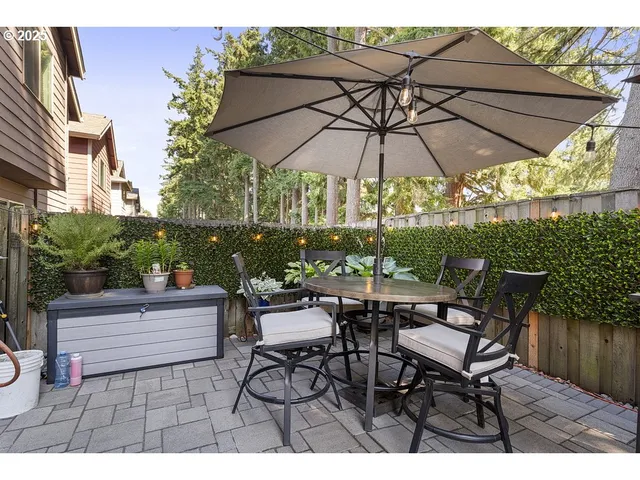a backyard view of a house with table and chairs under an umbrella