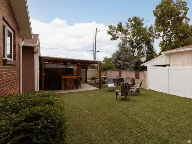 8252 Wood Street Midvale, UT 84047 - Photo 24 of 40 Expansive backyard featuring a covered patio with a built-in bar, artificial turf, and a white privacy fence
